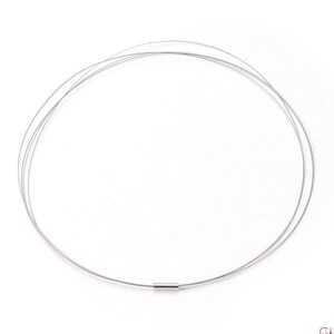 May include: A silver necklace with a thin, delicate chain. The chain is made of multiple strands of wire that are twisted together. The necklace has a simple, minimalist design.