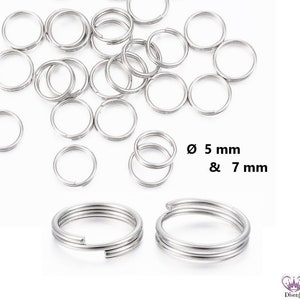 May include: A close-up of a pile of silver jump rings in two sizes: 5 mm and 7 mm. The rings are arranged in a random pattern on a white background.