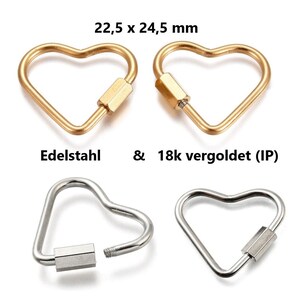 Könnte beinhalten: Vier herzförmige Karabinerverschlüsse. Zwei sind goldfarben und zwei silberfarben. Die goldenen Verschlüsse sind 18k vergoldet. Die Verschlüsse messen 22,5 x 24,5 mm. Der Text "Edelstahl & 18k vergoldet (IP)" ist sichtbar.