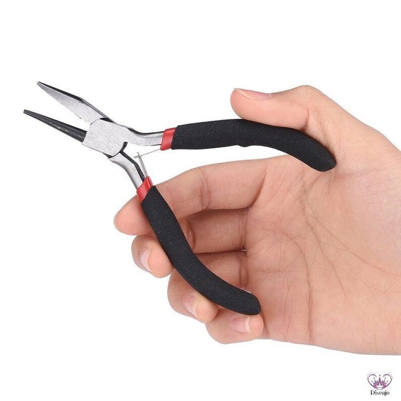 Puede incluir: Un par de alicates de joyer&iacute;a plateados con mangos de goma negra y detalles rojos. Los alicates se sostienen en una mano.