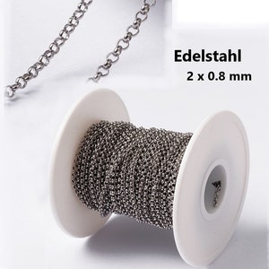 Könnte beinhalten: Eine Spule silberner Edelstahlkette, 2 mm breit und 0,8 mm dick. Die Kette ist um eine weiße Kunststoffspule gewickelt.