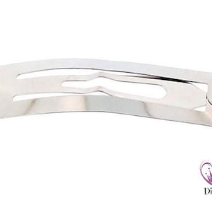 Könnte beinhalten: Eine silberne Haarklammer aus Metall mit einer gebogenen Form und einem einzigen Zahn.