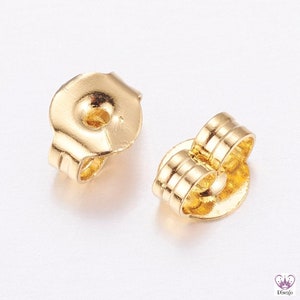 May include: Two gold-toned earring backs. The earring backs are designed to be used with post earrings. The backs are made of metal and have a smooth finish.