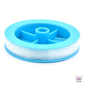 Könnte beinhalten: Eine Spule mit klarem elastischem Faden, die um eine blaue Plastikspule gewickelt ist.