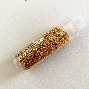 May include: A clear plastic bottle filled with 2000 gold-colored beads. The bottle has a label that reads "2000 St&uuml;ck in praktischer Aufbewahrungsflasche".