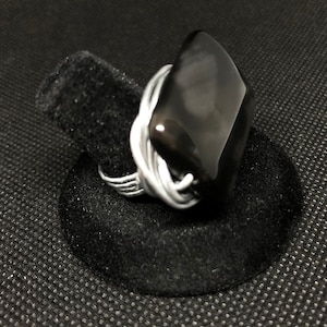 May include: A silver wire wrapped ring with a black rectangular gemstone.