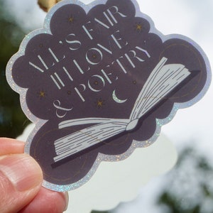 May include: A holographic sticker with a dark purple background featuring a white open book with the text "All's Fair in Love & Poetry" in white with gold stars and a crescent moon.