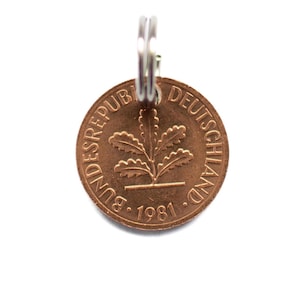 May include: A copper-colored German coin with the inscription "Bundesrepublik Deutschland" and the year "1981" on it. The coin features an oak leaf design.