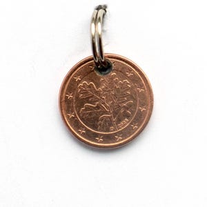 May include: A copper-coloured 1 cent Euro coin featuring an oak leaf design and the year 2005 inscribed on it.