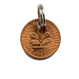 May include: A copper-coloured coin with the inscription "Bundesrepublik Deutschland" and the year "1982" around the edge. The coin features a stylised oak leaf design in the centre.