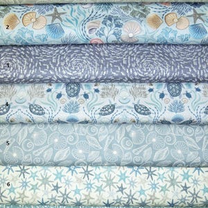 Könnte beinhalten: Sieben Stoffmuster mit maritimen Designs. Muster umfassen Muscheln, Seesterne und Fische in Blau-, Weiß- und Grautönen. Die Stoffe sind wahrscheinlich aus Baumwolle oder Leinen, geeignet für verschiedene Bastelprojekte.