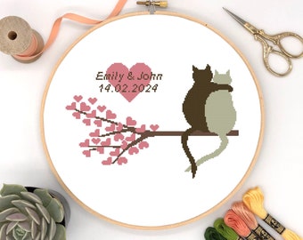 Puede incluir: Patrón de punto de cruz con dos gatos abrazándose en una rama con corazones rosas. El texto "Emily & John 14.02.2024" está por encima de los gatos.