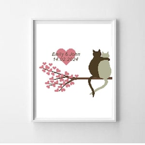 May include: A cross-stitch pattern featuring two cats sitting on a branch with pink hearts. The text "Emily & John 14.02.2024" is above the cats.