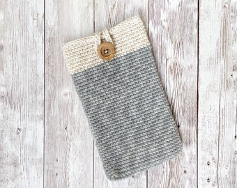 May include: A grey and cream crocheted phone case with a wooden button.