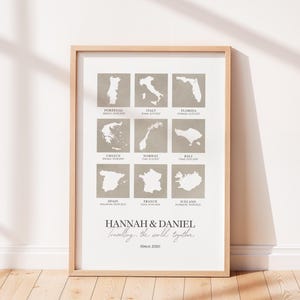 May include: A framed print with a light wood frame. The print shows a grid of nine country outlines in a neutral tone, including Portugal, Italy, and Florida. The names "HANNAH & DANIEL" and the phrase "Travelling the world together Since 2010" are also printed.