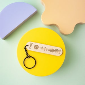 May include: A yellow circle with a wooden keychain featuring a barcode and the text "W & M". The keychain is attached to a black metal ring.