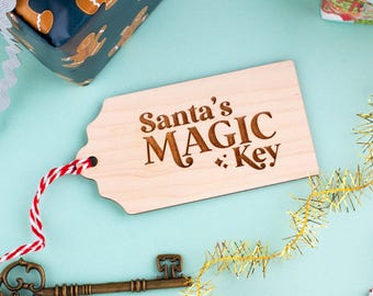 May include: A wooden tag with the words "Santa's MAGIC Key" engraved on it. The tag is attached to a red and white string. A vintage-style key and wrapped gifts are also visible.