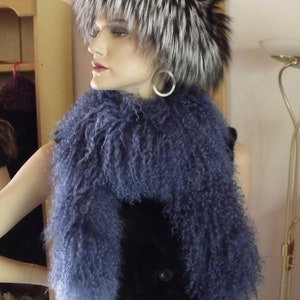 Peut inclure: Un mannequin portant une écharpe en fausse fourrure bleue et un chapeau en fourrure noir et blanc. Le chapeau a une forme longue et pointue et est bordé d'une bande noire.