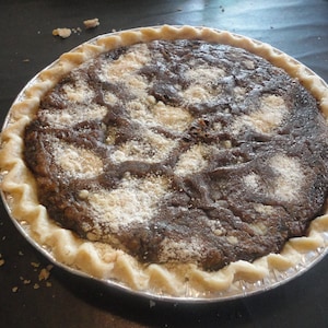 May include: A chocolate pie with a flaky crust and a light dusting of powdered sugar on top.