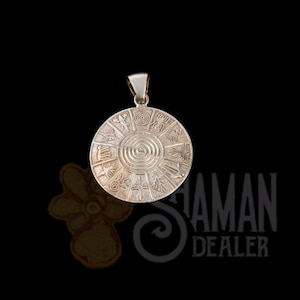 Puede incluir: Un colgante circular de metal plateado con un diseño de espiral central rodeado por doce segmentos distintos, cada uno con un símbolo grabado único. El colgante incluye una reasa en la parte superior para sujetarlo a una cadena.