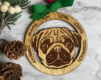 May include: A wooden Christmas ornament featuring a pug dog silhouette with the words "Playful Fun Loyal Loving Adorable Companion" around the edge.
