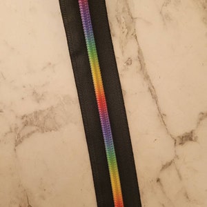 May include: Black zipper tape with a rainbow colored stripe down the center.