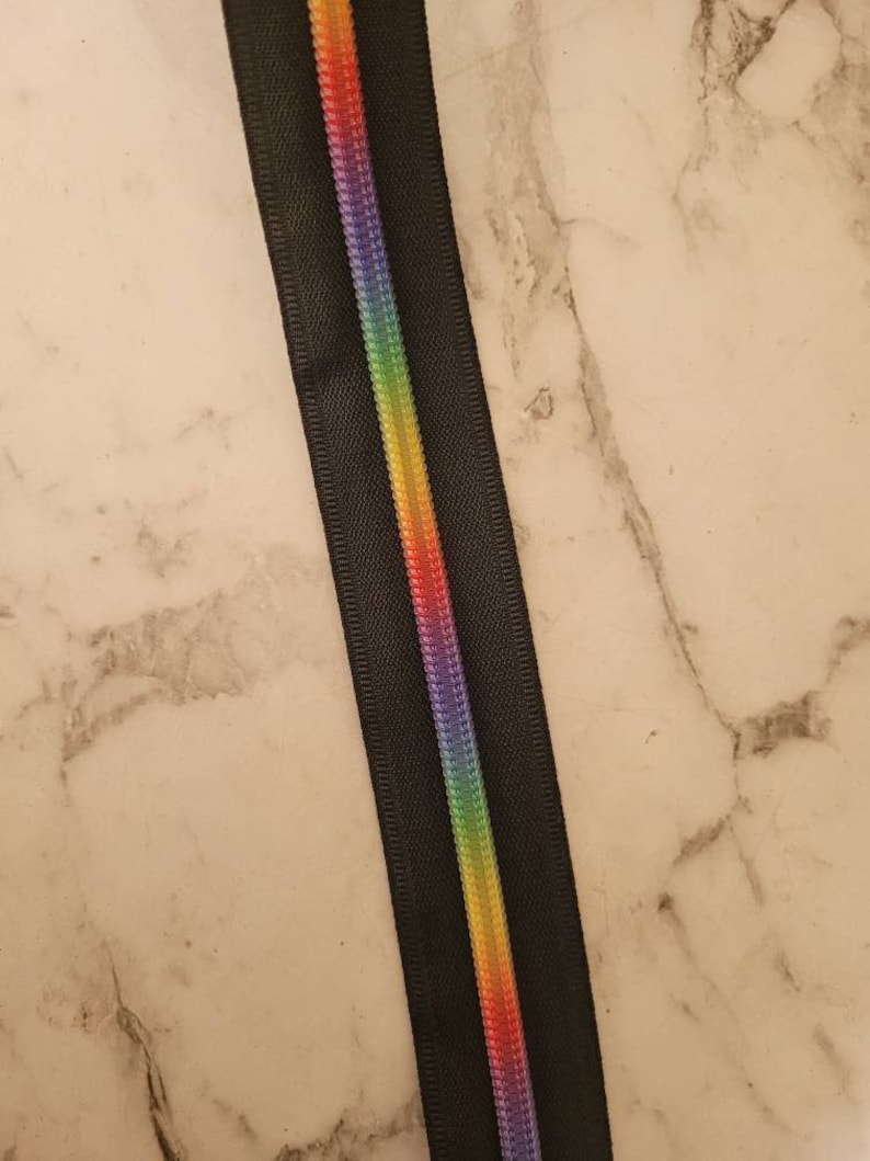 May include: Black zipper tape with a rainbow colored stripe down the center.