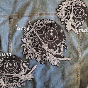 May include: Three embroidered iron-on patches featuring a witch's hat, broom, moon, and stars. The patches are labelled "small", "medium", and "large".