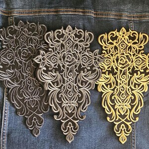May include: Three embroidered patches with ornate floral designs. One patch is gold, one is silver, and one is dark gray. The patches are on a denim jacket.