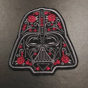 以下が含まれることがあります： 赤いバラと花のデザインが施された、ダース・ベイダーのヘルメットの黒とグレーの刺繍パッチ