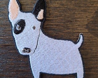 Puede incluir: Un parche bordado de color azul claro de un perro bull terrier con orejas negras y nariz negra. El perro tiene un ojo negro y una oreja rosa.