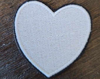 Puede incluir: Parche de fieltro blanco en forma de corazón con un contorno cosido negro.