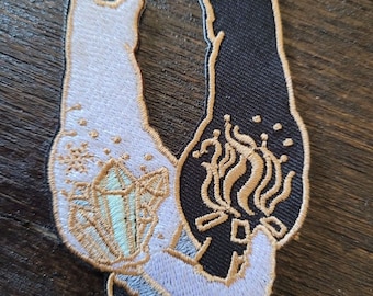 Puede incluir: Parche bordado con dos gatos enfrentados, uno blanco con un diseño de cristal y el otro negro con un diseño de remolino. Las colas de los gatos están entrelazadas, formando un corazón.