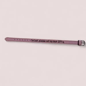 Puede incluir: Un collar de perro de cuero rosa con el texto "Estoy perdido, por favor llama a mi mamá 07716" grabado en él.