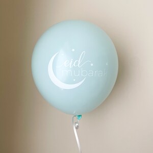 May include: A light blue balloon with a white crescent moon and stars, and the text "eid mubarak" in white cursive.