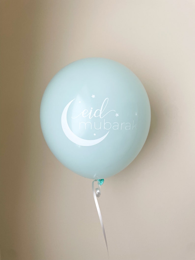 May include: A light blue balloon with a white crescent moon and stars, and the text "eid mubarak" in white cursive.