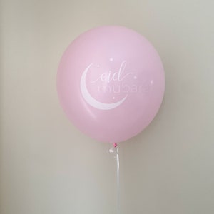 May include: A pink balloon with a white crescent moon and stars, and the text "eid mubarak" written in a cursive font.