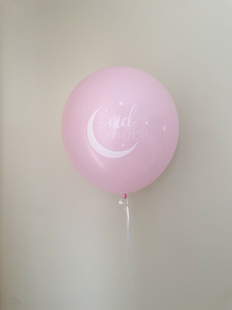 May include: A pink balloon with a white crescent moon and stars, and the text "eid mubarak" written in a cursive font.
