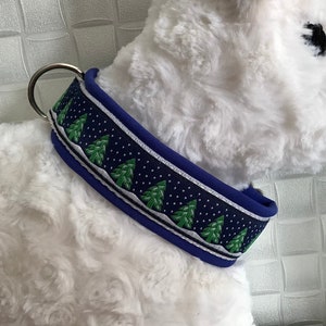 Könnte beinhalten: Ein blaues Hundehalsband mit einem weißen und grünen Weihnachtsbaum-Muster. Das Halsband ist aus weichem, gepolstertem Material und hat einen silbernen Metallring.