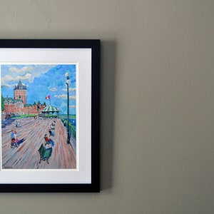 May include: A framed painting of a waterfront scene with a large building in the background, people walking on a boardwalk, and a blue sky with white clouds.