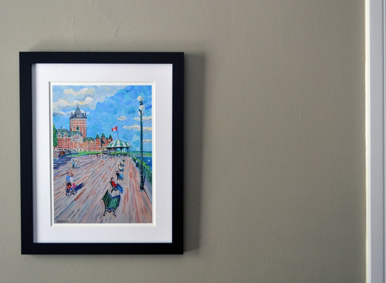 May include: A framed painting of a waterfront scene with a large building in the background, people walking on a boardwalk, and a blue sky with white clouds.