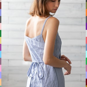 May include: A light blue linen dress with thin straps and a tie at the waist. The dress is made of a soft, breathable fabric and has a relaxed fit.