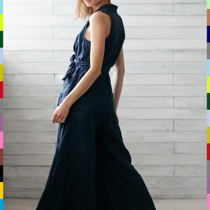 K&ouml;nnte beinhalten: Ein marineblaues &auml;rmelloses Oberteil und eine Hose mit weitem Bein. Das Oberteil hat eine Schleife an der Taille und einen Kragen. Die Hose ist bodenlang. Das Outfit ist aus einem strukturierten Stoff gefertigt. Das Model tr&auml;gt hellbraune Sandalen.