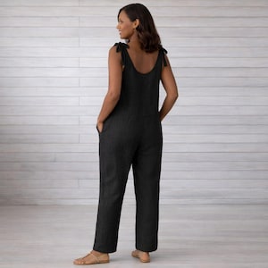 以下が含まれることがあります： 肩紐を結んだ黒いジャンプスーツ、ラウンドネック、ポケット付き。 モデルはジャンプスーツを着て、カメラに背を向けて立っています。 ジャンプスーツはテクスチャード加工された生地で作られており、ゆったりとしたフィット感です。