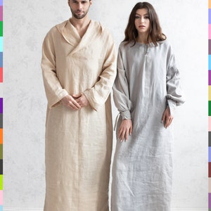 May include: Two people wearing long, loose-fitting linen robes. The person on the left is wearing a beige robe, and the person on the right is wearing a gray robe. Both people are standing on a white floor in front of a white wall.