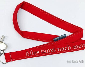 May include: Red lanyard with white stitching and the text "Alles tanzt nach mein" and "von Tante Polli" embroidered on it. A silver whistle is attached to the lanyard.