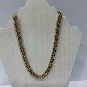 May include: A gold-toned chain necklace featuring a series of interlocking oval links. The metal has a polished finish with subtle texture throughout the surface of each individual link, creating a continuous, uniform pattern along the entire length.