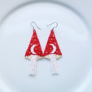 Mushroom patterned beaded earrings on white background