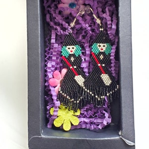 The earrings are shown in a black fold and tuck jewelry box. The paddings are purple and paper flowers are added to the packaging.