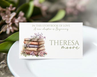 May include: A white place card with the text "In this storybook of love, A new chapter is beginning." A stack of books with floral accents is on the left, and the name "Theresa Moore" is on the right. The card is on a white plate.